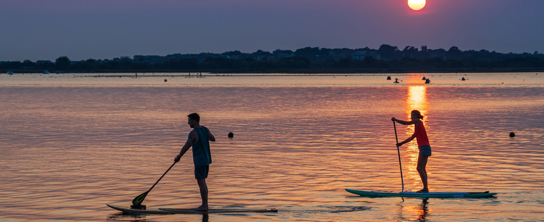 Man and a woman paddle boarding in UK