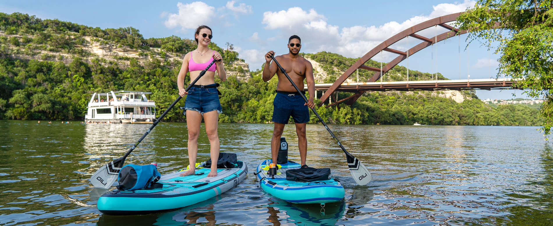 Man and a woman wearing a polarized sunglasses SUPing near a bridge