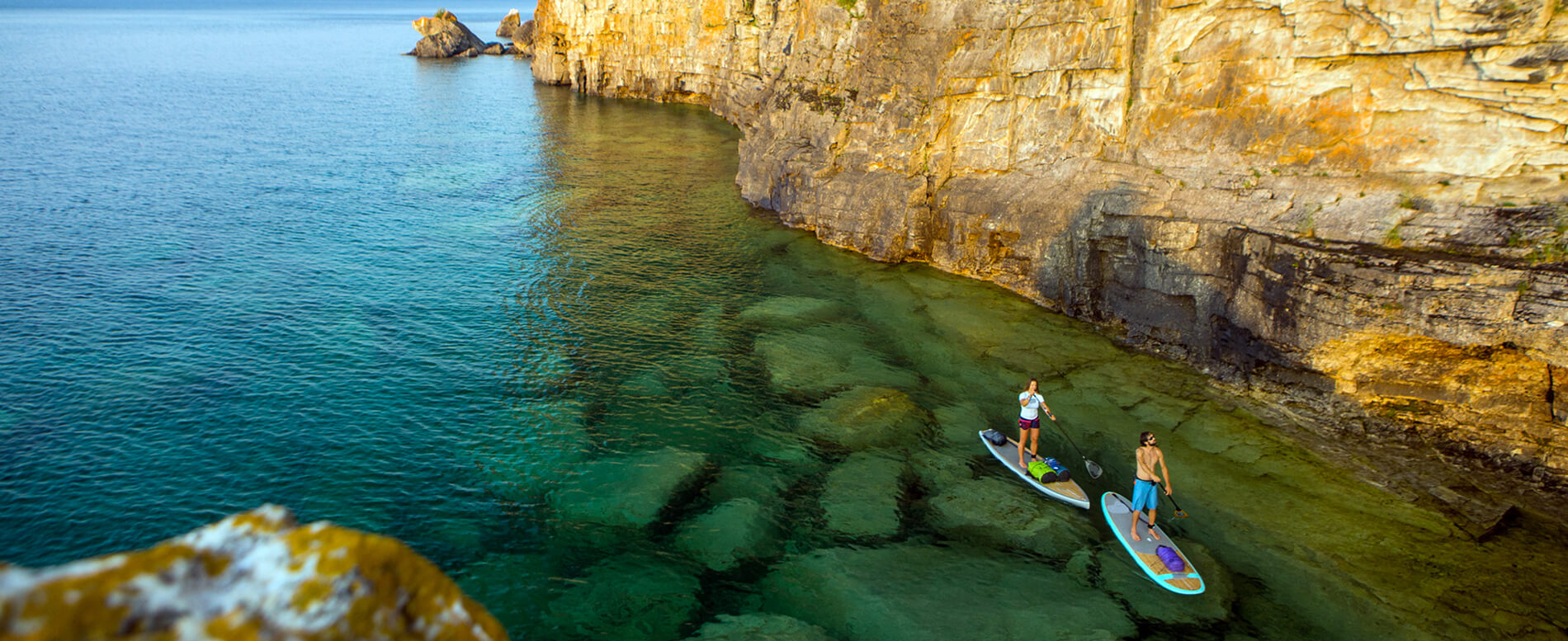 Attractive young couple stand up paddle boarding in Ontario Canada